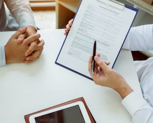 Confident female doctor reviews patient medical information and pointing to medical forms.